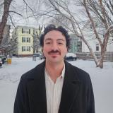 Gabriel standing outside in the snow with houses and trees behind.